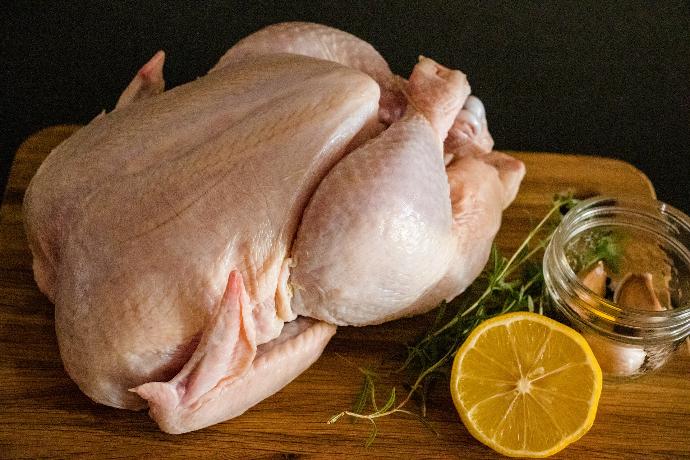 carne de pollo cruda en una tabla de cortar de madera marron